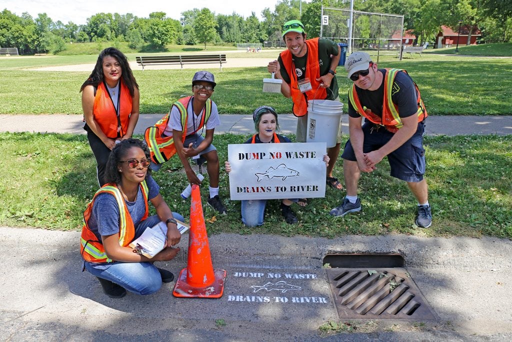 Students with the storm drain warning they stenciled.